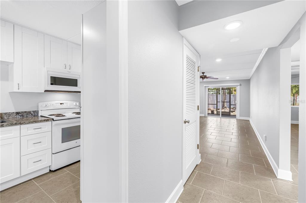 A view from a hallway looking into a white kitchen and a tiled living area — 4435 1ST STREET NE UNIT 104, ST PETERSBURG, FL