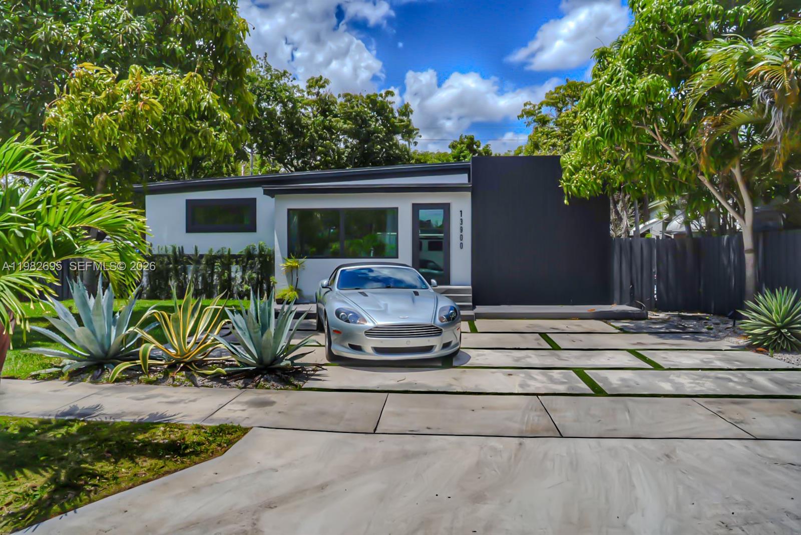 A modern single-story house with a silver convertible parked on a concrete paver driveway — 13900 NE 16th Ct, North Miami FL 33181, NORTH MIAMI, FL