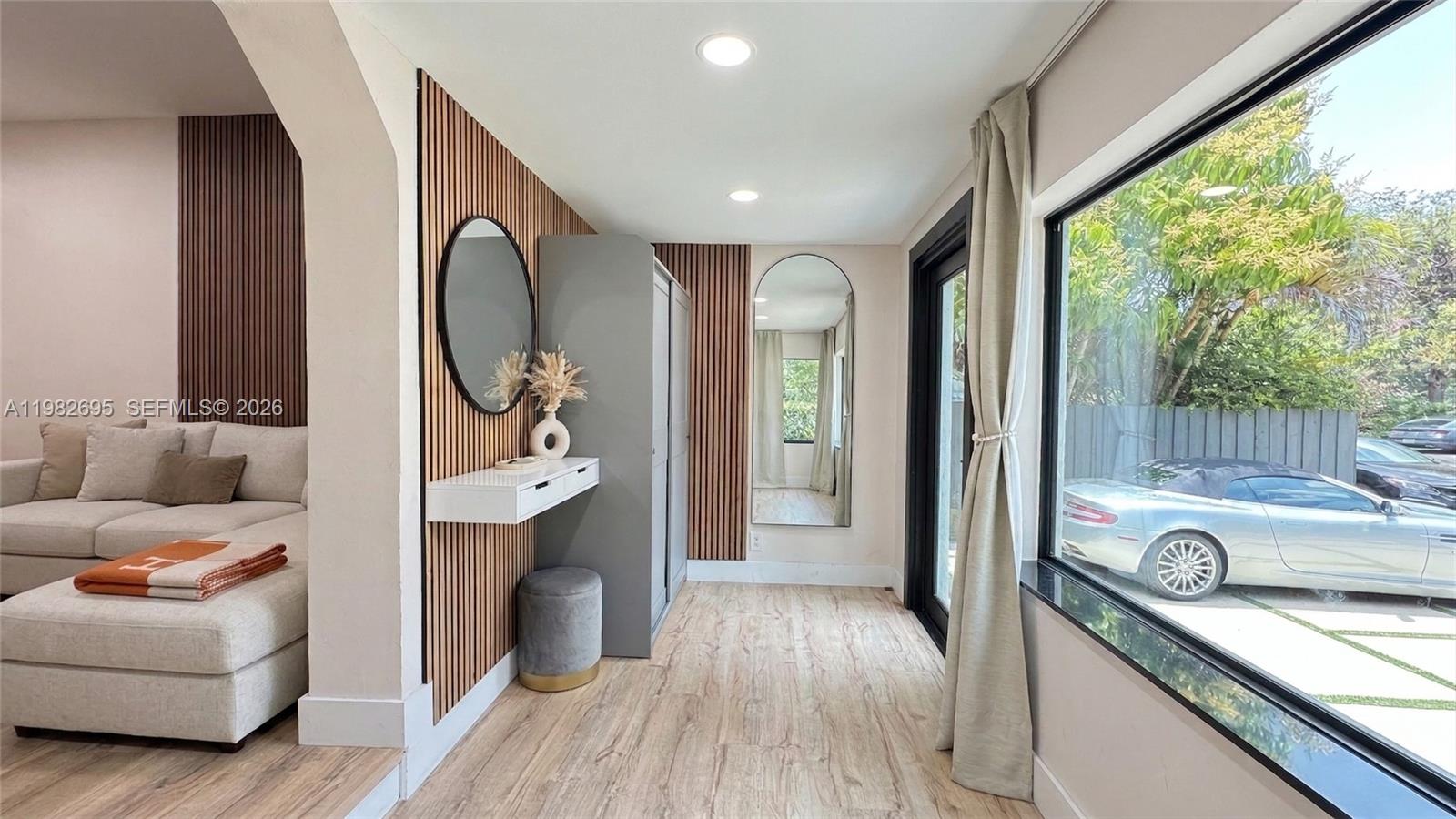 A modern room features wood-slat wall panels, a floating console, mirrors, and a large window — 13900 NE 16th Ct, North Miami FL 33181, NORTH MIAMI, FL