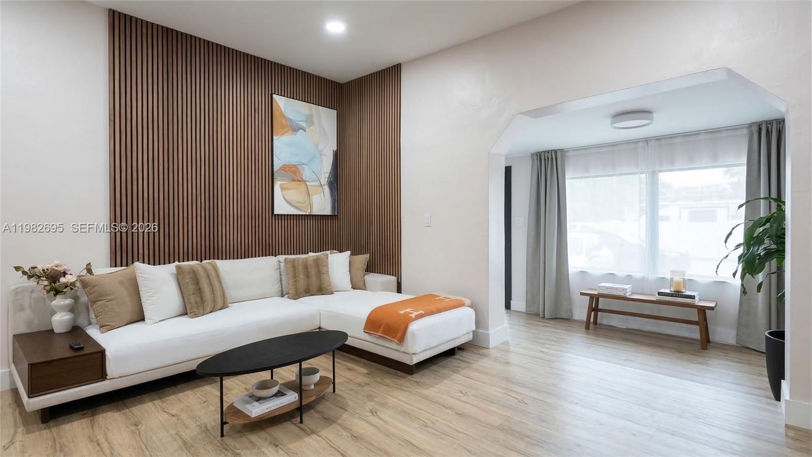 A living room features a white sectional sofa against a wood-slat accent wall — 13900 NE 16th Ct, North Miami FL 33181, NORTH MIAMI, FL