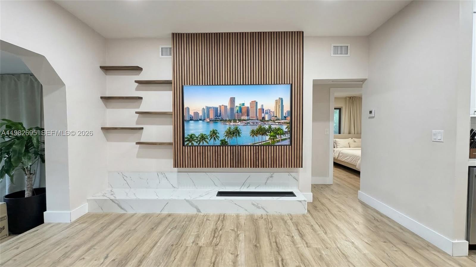 A living room features a wood-slat accent wall with a television and marble fireplace hearth — 13900 NE 16th Ct, North Miami FL 33181, NORTH MIAMI, FL