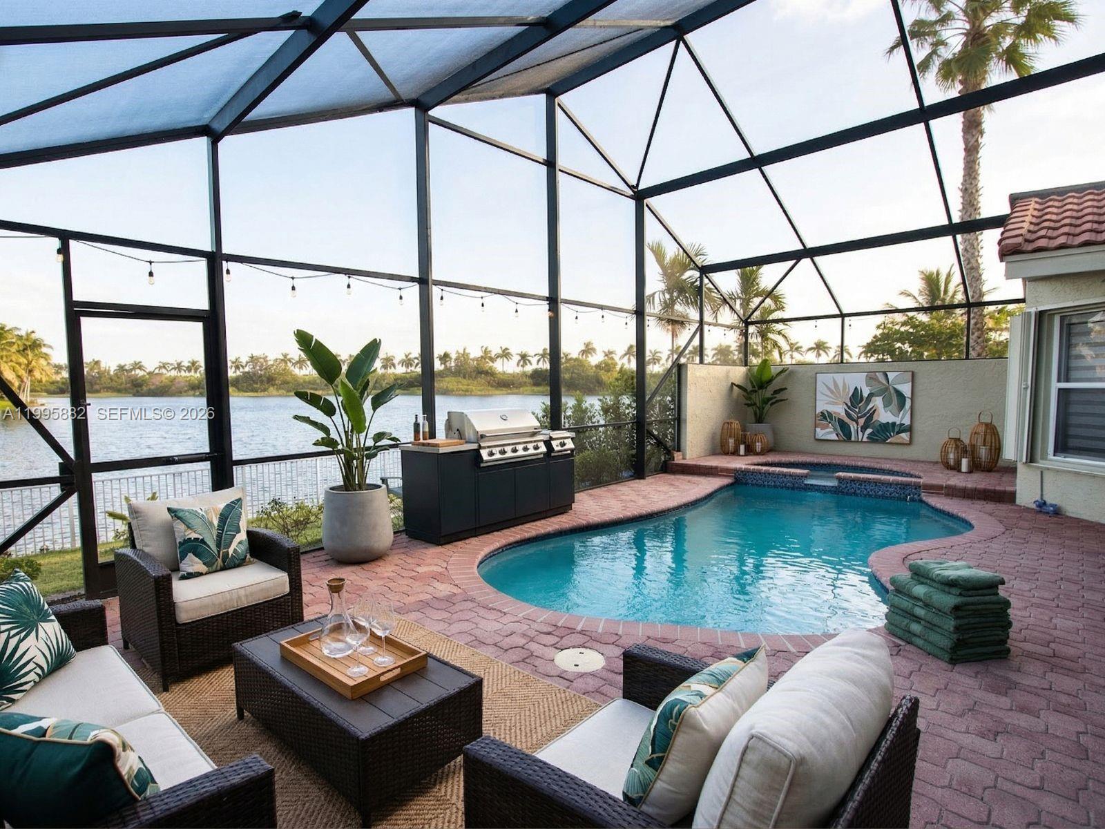 A screened-in patio features a swimming pool, outdoor kitchen, and seating area overlooking a lake — 18096 SW 29th St, Miramar FL 33029, MIRAMAR, FL