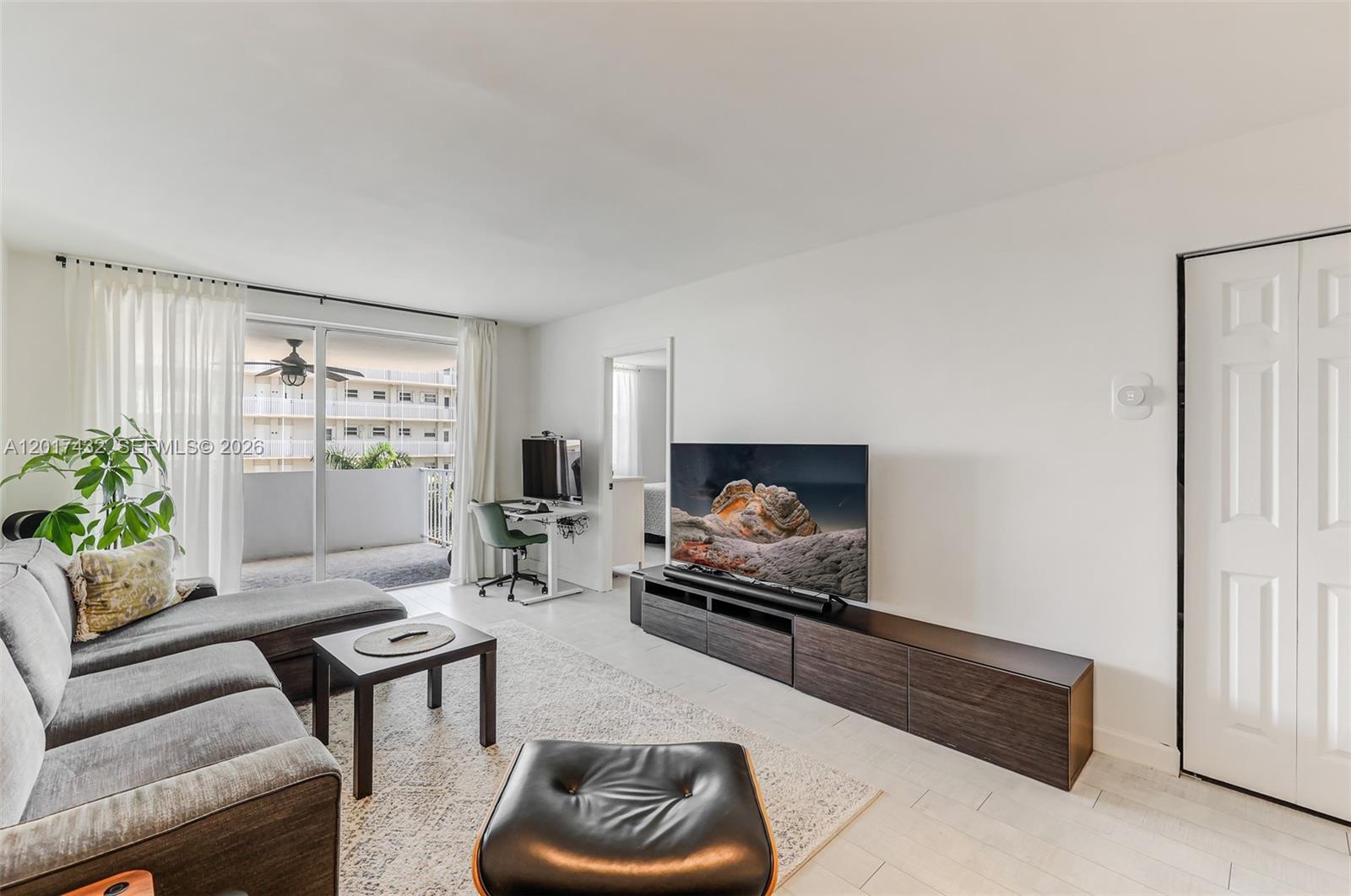 A living room features a grey sectional sofa, a television console, and a balcony view — 1331 Lincoln Rd # 704, Miami Beach FL 33139, MIAMI BEACH, FL