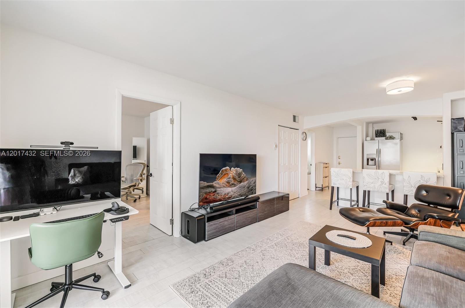 A living room features a television, a desk, a lounge chair, and an open kitchen — 1331 Lincoln Rd # 704, Miami Beach FL 33139, MIAMI BEACH, FL
