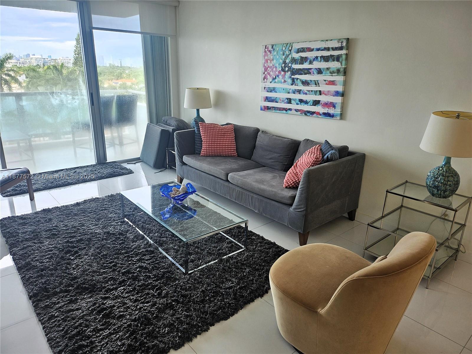 A living room features a gray sofa, a glass coffee table, and a balcony view — 5161 Collins Ave # 707, Miami Beach FL 33140, MIAMI BEACH, FL