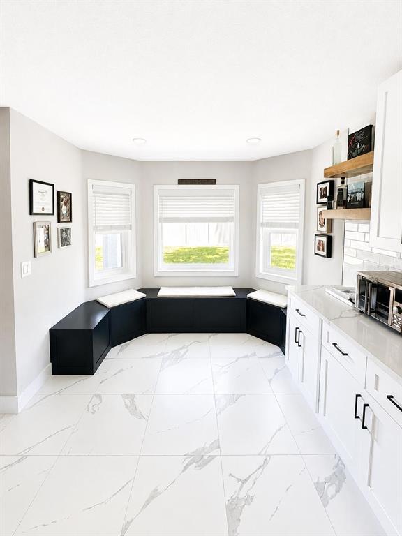 A kitchen features white marble-look tile floors, white cabinets, and a black built-in window seat — 14 LAMOYNE LANE, PALM COAST, FL