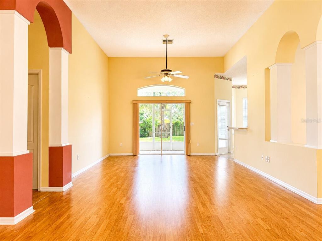 A bright living room features light-colored walls, hardwood flooring, a ceiling fan, and sliding glass doors — 1995 EMERALD GREEN CIRCLE, OVIEDO, FL