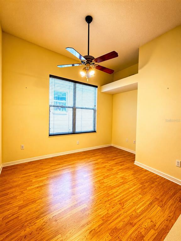 An empty room with yellow walls, wood-look flooring, a ceiling fan, and a window — 1995 EMERALD GREEN CIRCLE, OVIEDO, FL