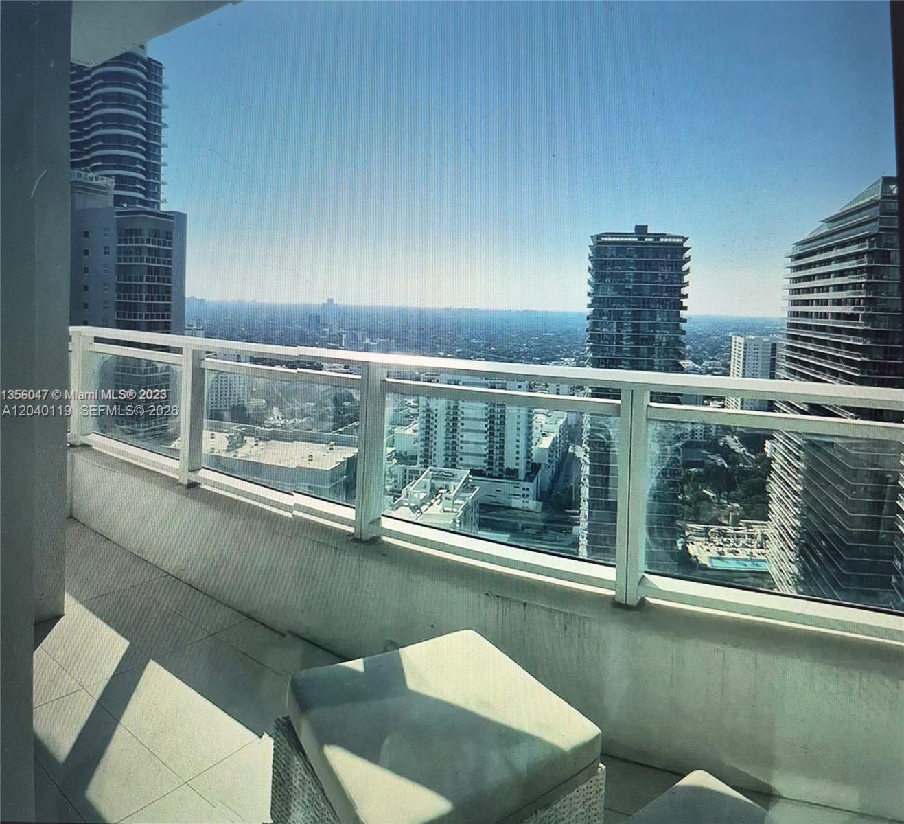 A balcony with a glass railing overlooks a dense urban skyline with several high-rise buildings — 1080 Brickell Ave # 3203, Miami FL 33131, MIAMI, FL