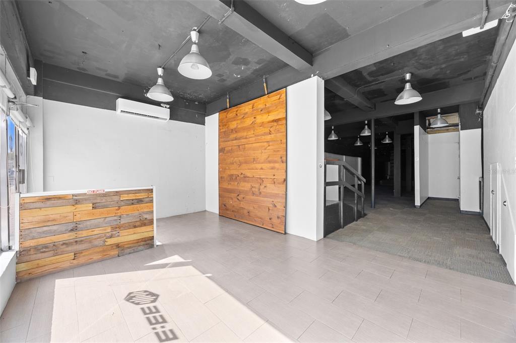 An empty commercial space features a wood-paneled accent wall, tiled flooring, and exposed ceiling lights — 322 MENDEZ VIGO, DORADO, PR