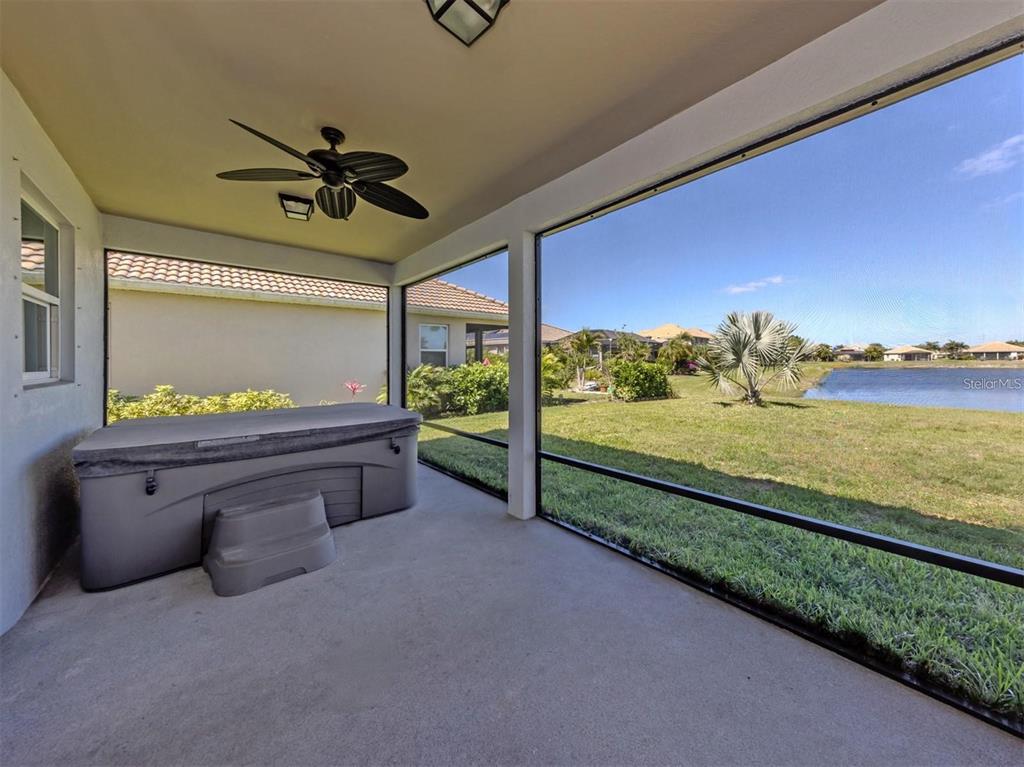 A screened-in patio features a hot tub, a ceiling fan, and a view of a pond — 2160 WEAVER BIRD LANE, VENICE, FL
