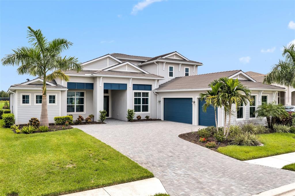 A two-story house with a paved driveway, blue garage doors, and palm trees in front — 8444 CANE BAY COURT, LAKEWOOD RANCH, FL