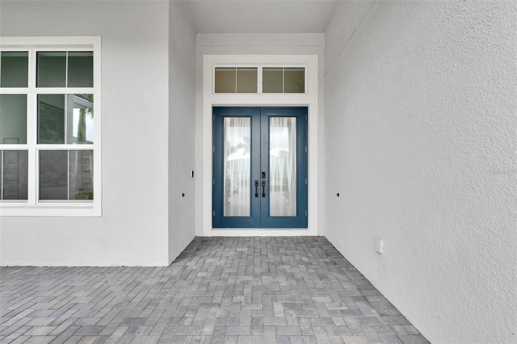 A blue double door with glass panels sits on a gray paver patio — 8444 CANE BAY COURT, LAKEWOOD RANCH, FL