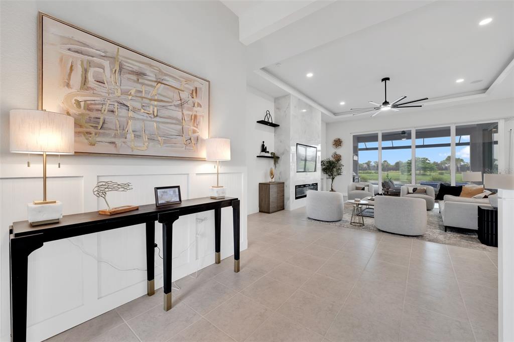 A modern entryway with a console table leads into an open-concept living room with tile floors — 8444 CANE BAY COURT, LAKEWOOD RANCH, FL