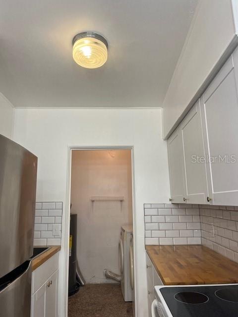 A kitchen features white cabinets, a wood countertop, subway tile backsplash, and a laundry closet — 1434 MINNESOTA AVENUE, WINTER PARK, FL