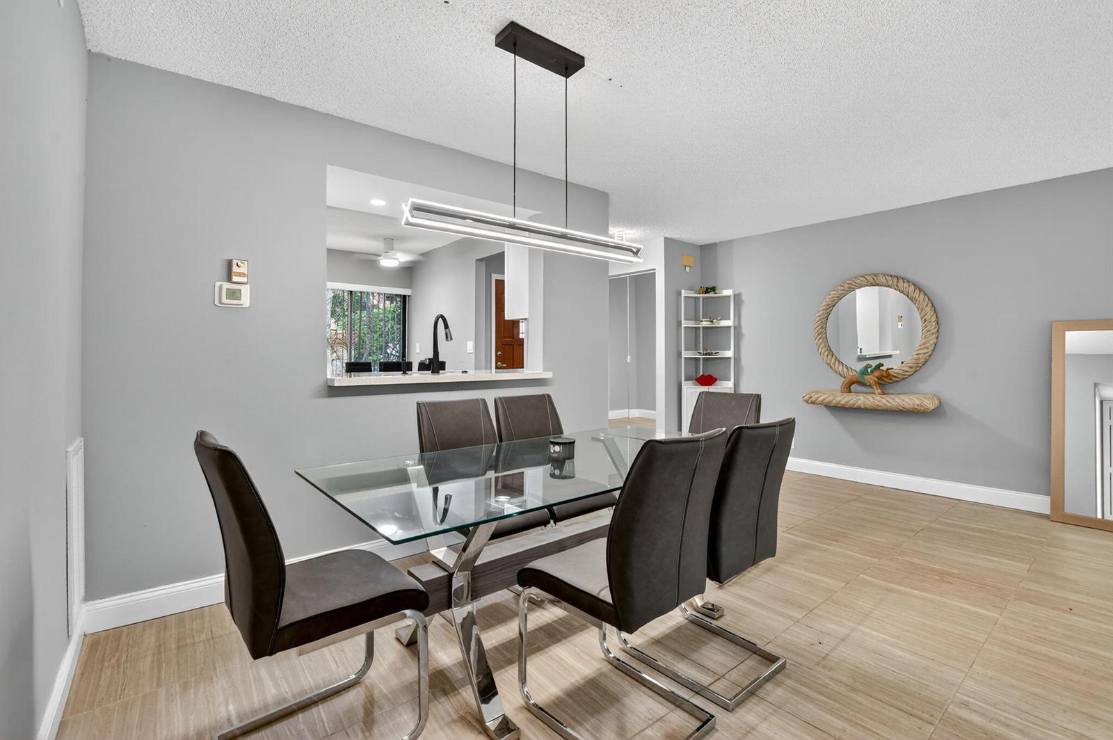 A dining room features a glass table, six chairs, a modern light fixture, and tile flooring — 7773 La Mirada Drive, Boca Raton FL 33433, BOCA RATON, FL