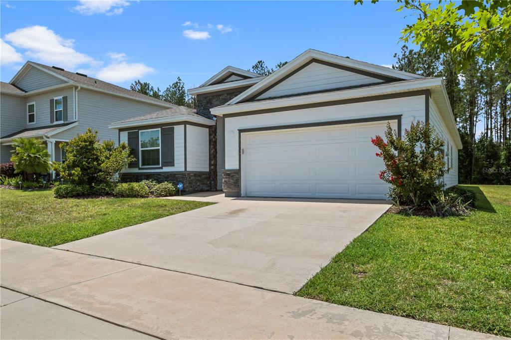 A single-story house with a white garage, stone accents, and a concrete driveway — 17387 NW 172ND AVENUE, ALACHUA, FL