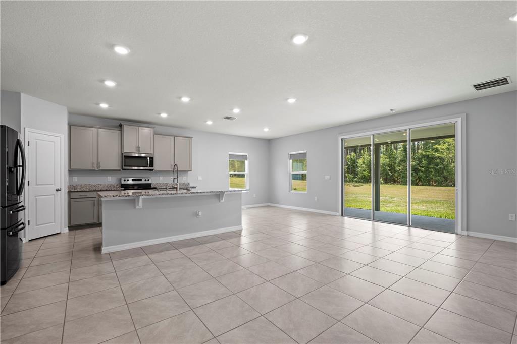 A kitchen with gray cabinets and a breakfast bar opens into a tiled living area — 17387 NW 172ND AVENUE, ALACHUA, FL