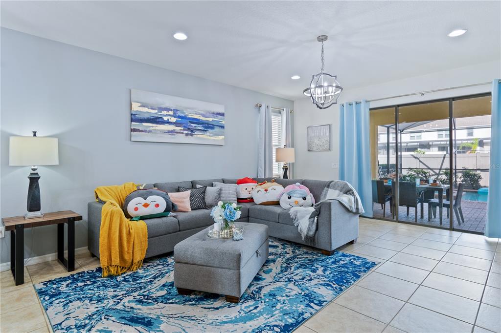 A living room features a grey sectional sofa, a blue patterned rug, and sliding glass doors — 8913 RHODES STREET, KISSIMMEE, FL