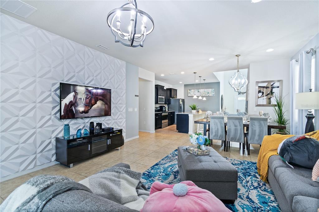 An open-concept living and dining area features a textured accent wall and tile flooring — 8913 RHODES STREET, KISSIMMEE, FL