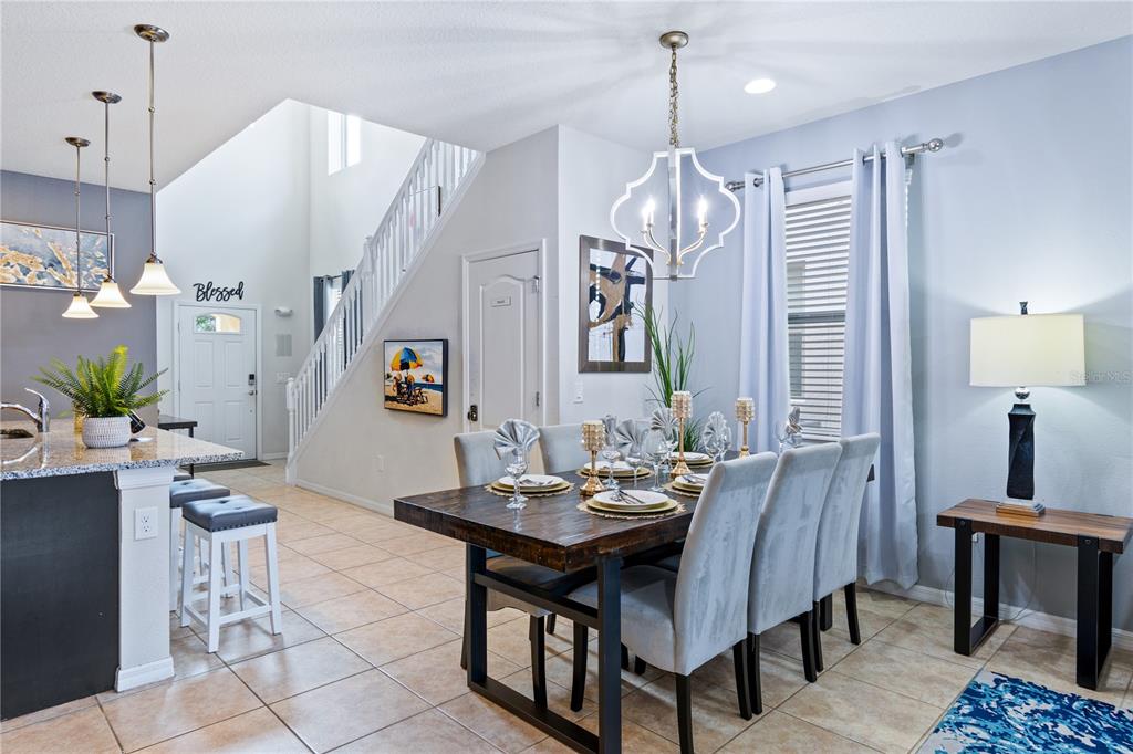 A dining area with a wooden table and grey chairs sits near a kitchen island — 8913 RHODES STREET, KISSIMMEE, FL