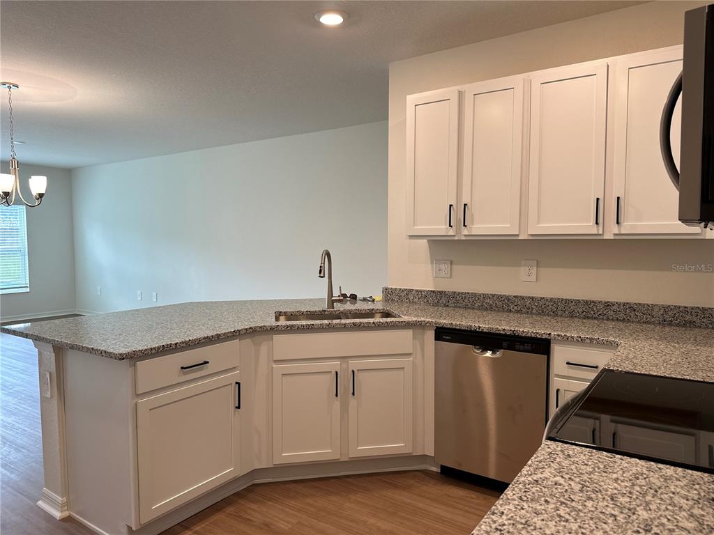 A kitchen features white cabinets, granite countertops, and stainless steel appliances — 9354 WESTSIDE HILLS DRIVE, DAVENPORT, FL