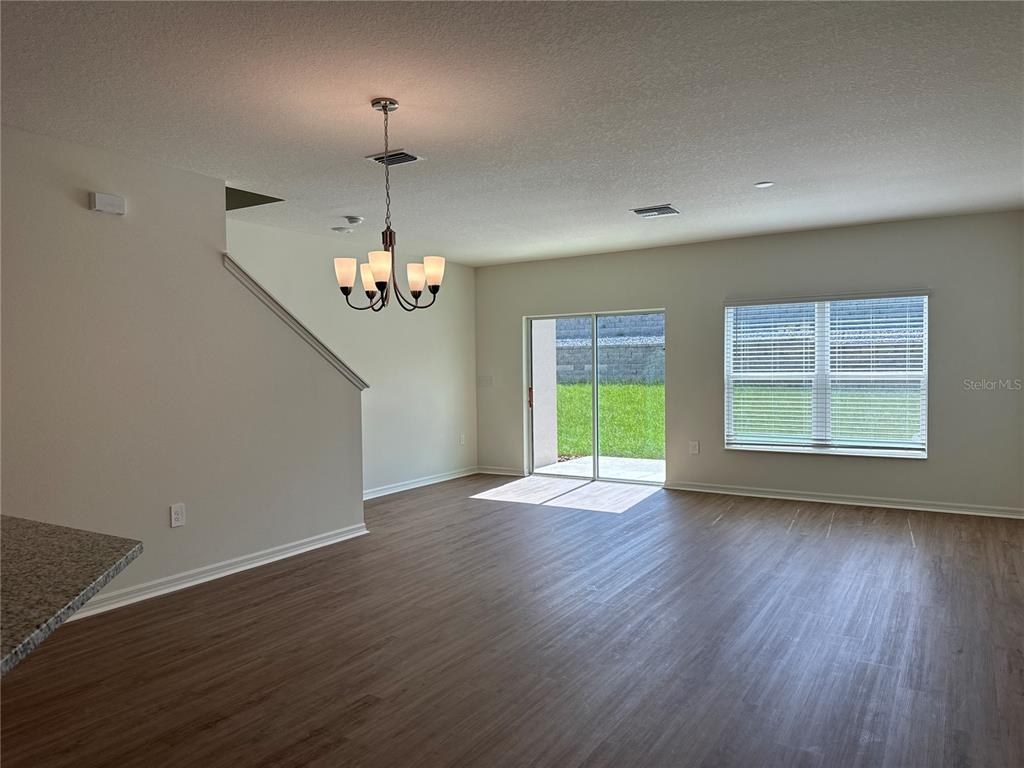 An open-concept living area features wood-look flooring, a dining chandelier, and sliding glass patio doors — 9354 WESTSIDE HILLS DRIVE, DAVENPORT, FL