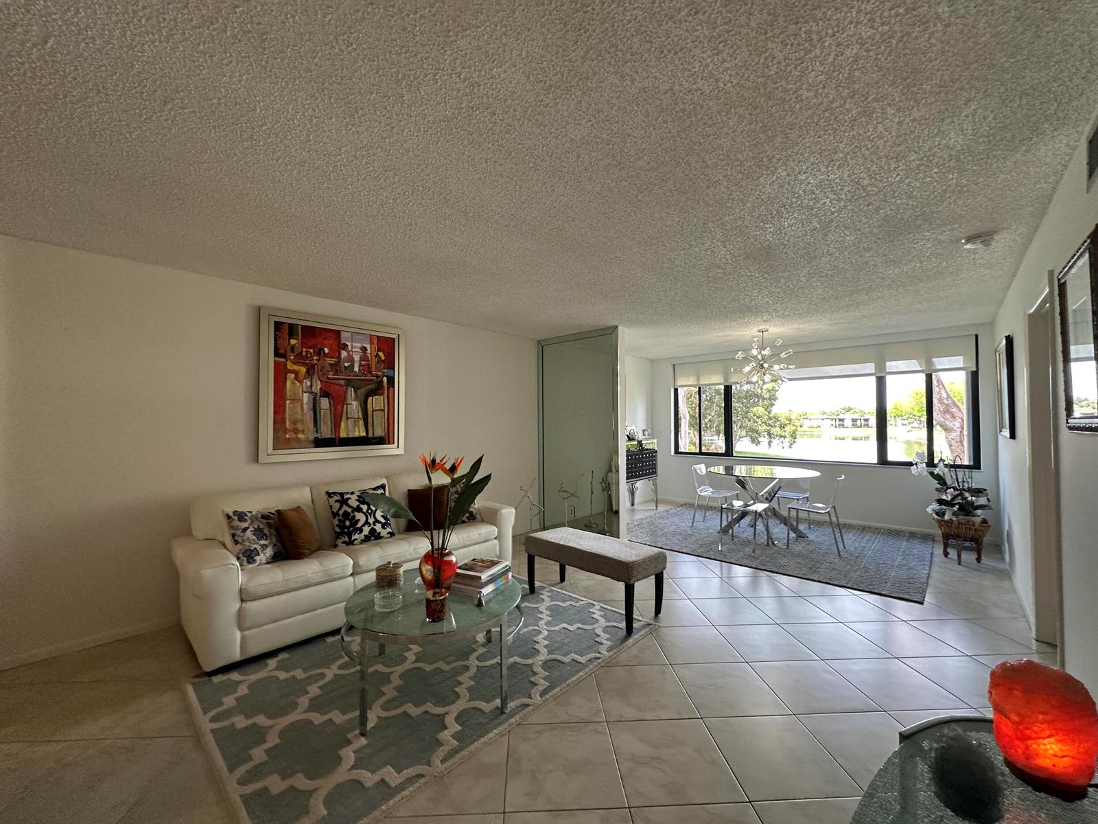 A living and dining area with tile floors, a white sofa, and a large window — 15075 Witney Road # 211, Delray Beach FL 33484, DELRAY BEACH, FL