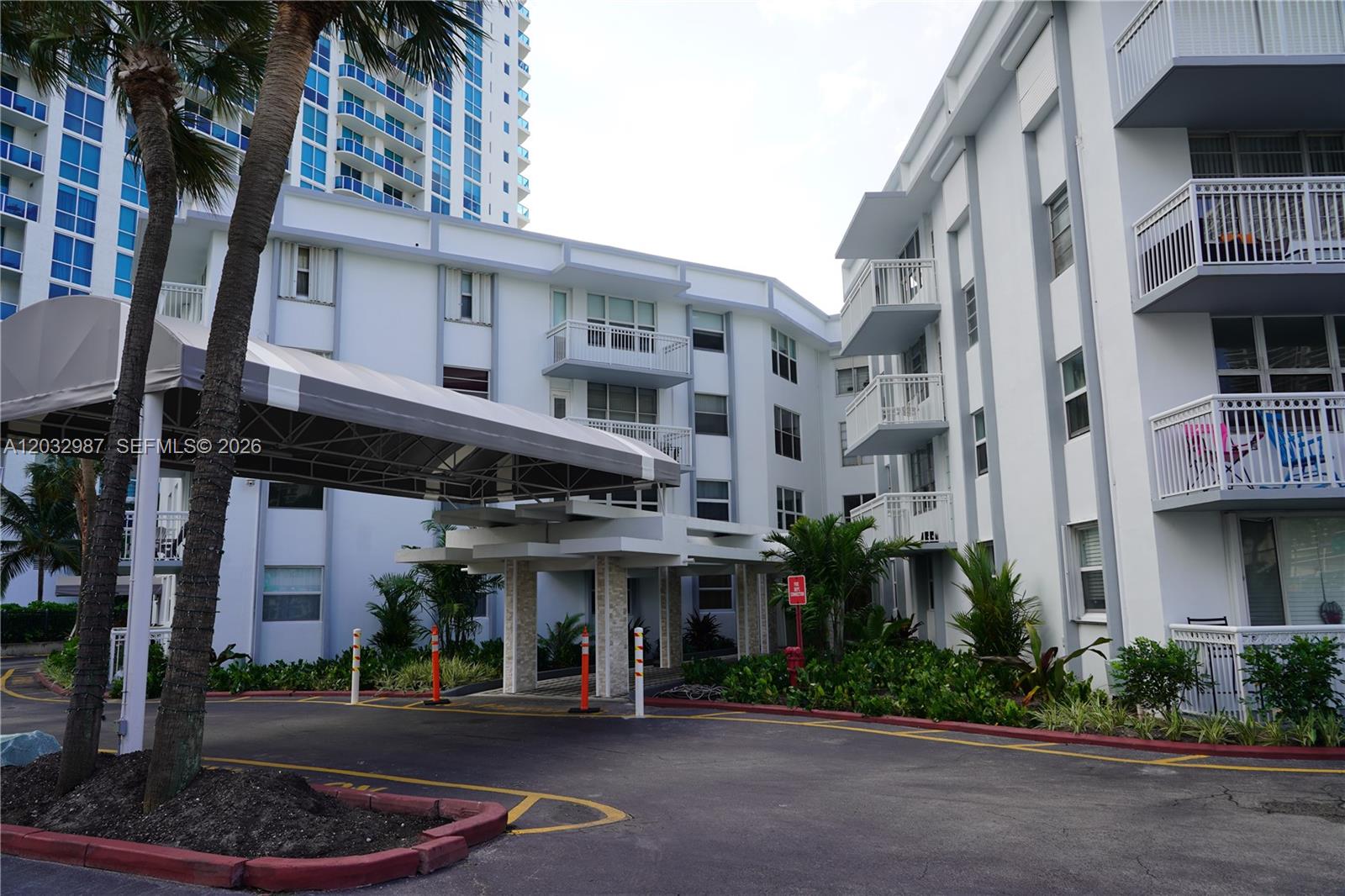 A multi-story apartment building features a covered driveway entrance and balconies with white railings — 1913 S Ocean Dr # 405, Hallandale Beach FL 33009, HALLANDALE BEACH, FL