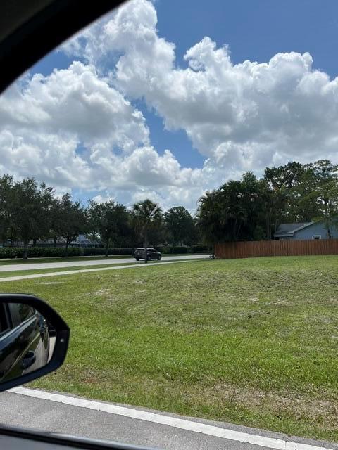 A grassy, vacant residential lot sits next to a road with trees and a fence — 1094 Primrose Lane, Wellington FL 33414, WELLINGTON, FL