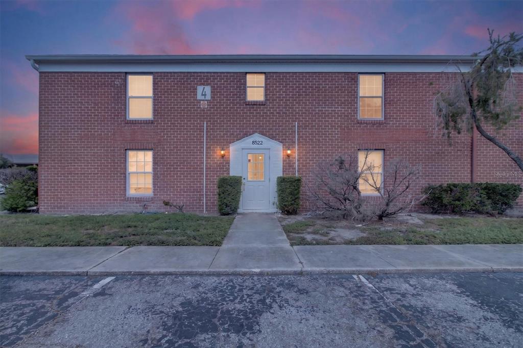 A two-story brick apartment building exterior with a central white door and parking lot — 8522 10TH STREET N UNIT D, ST PETERSBURG, FL