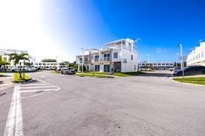 A street view of modern multi-story townhouses under a clear blue sky — HOMESTEAD, FL