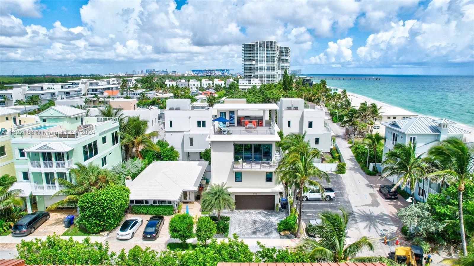 An aerial view shows a modern multi-story house with a rooftop deck near the ocean — 305 Oak St, Hollywood FL 33019, HOLLYWOOD, FL