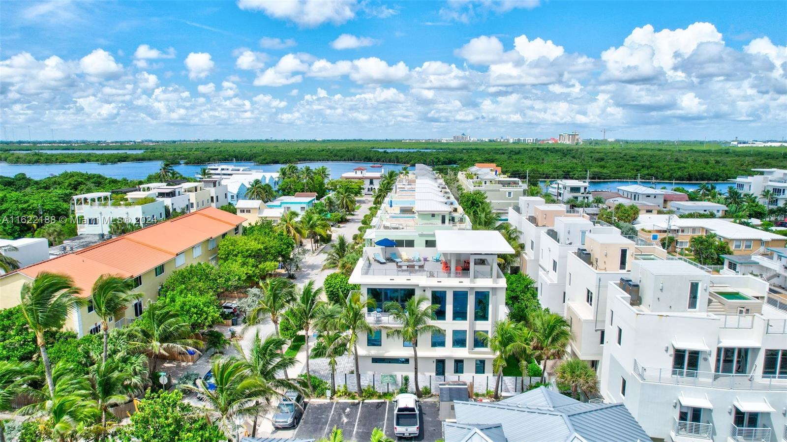 An aerial view shows modern multi-story townhouses surrounded by palm trees near a waterway — 305 Oak St, Hollywood FL 33019, HOLLYWOOD, FL