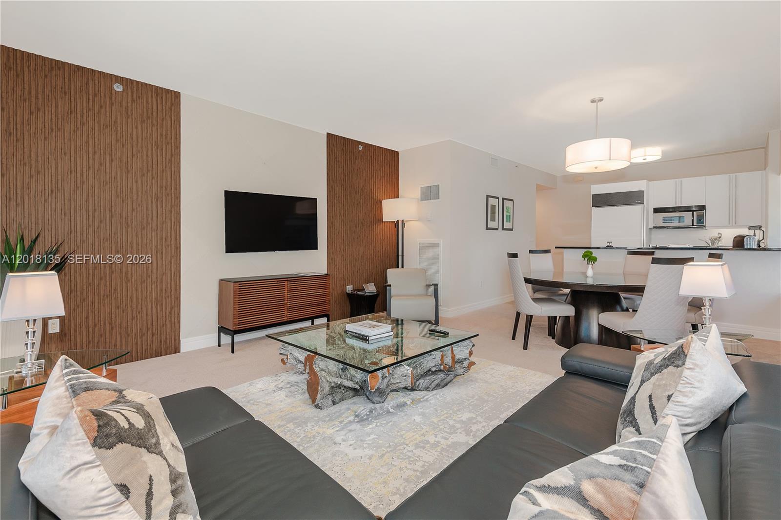 A living room features a glass-topped coffee table with a wood base and wood-paneled walls — 1435 Brickell Ave # 3012, Miami FL 33131, MIAMI, FL