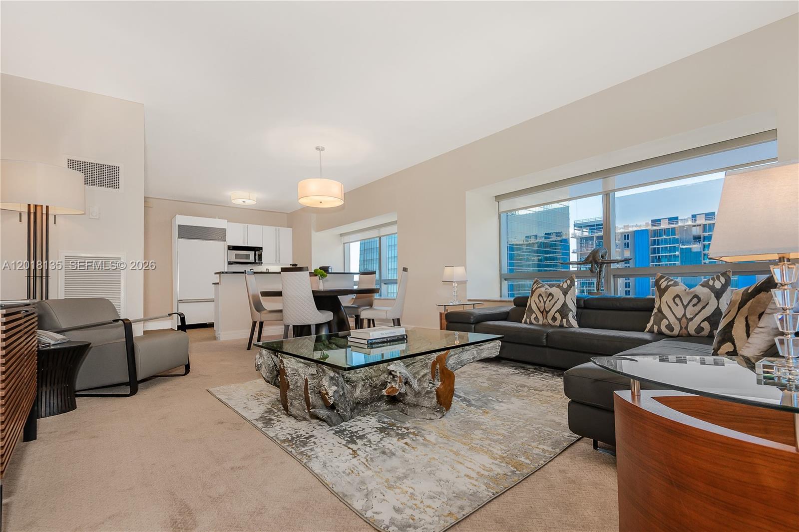 A living and dining area features a glass-topped root coffee table and city views — 1435 Brickell Ave # 3012, Miami FL 33131, MIAMI, FL