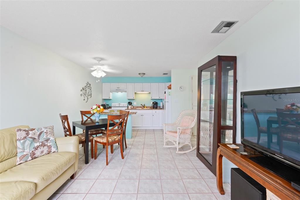 A living room and dining area with tile floors, white cabinets, and a wicker chair — 4351 TAHITIAN GARDENS CIRCLE UNIT C, HOLIDAY, FL