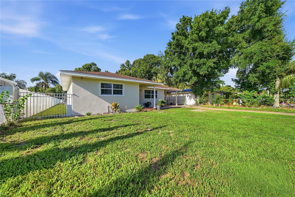 A single-story house with a light-colored exterior and a grassy yard under a blue sky — 3006 W SAINT CONRAD STREET, TAMPA, FL
