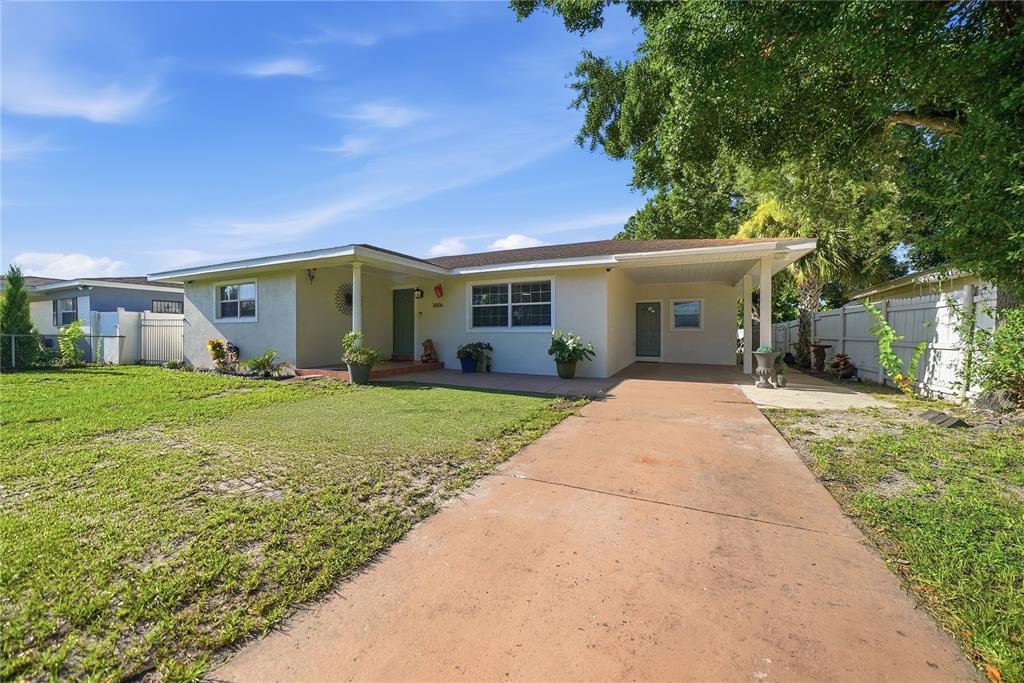 A single-story house with a light-colored exterior, a carport, and a concrete driveway — 3006 W SAINT CONRAD STREET, TAMPA, FL