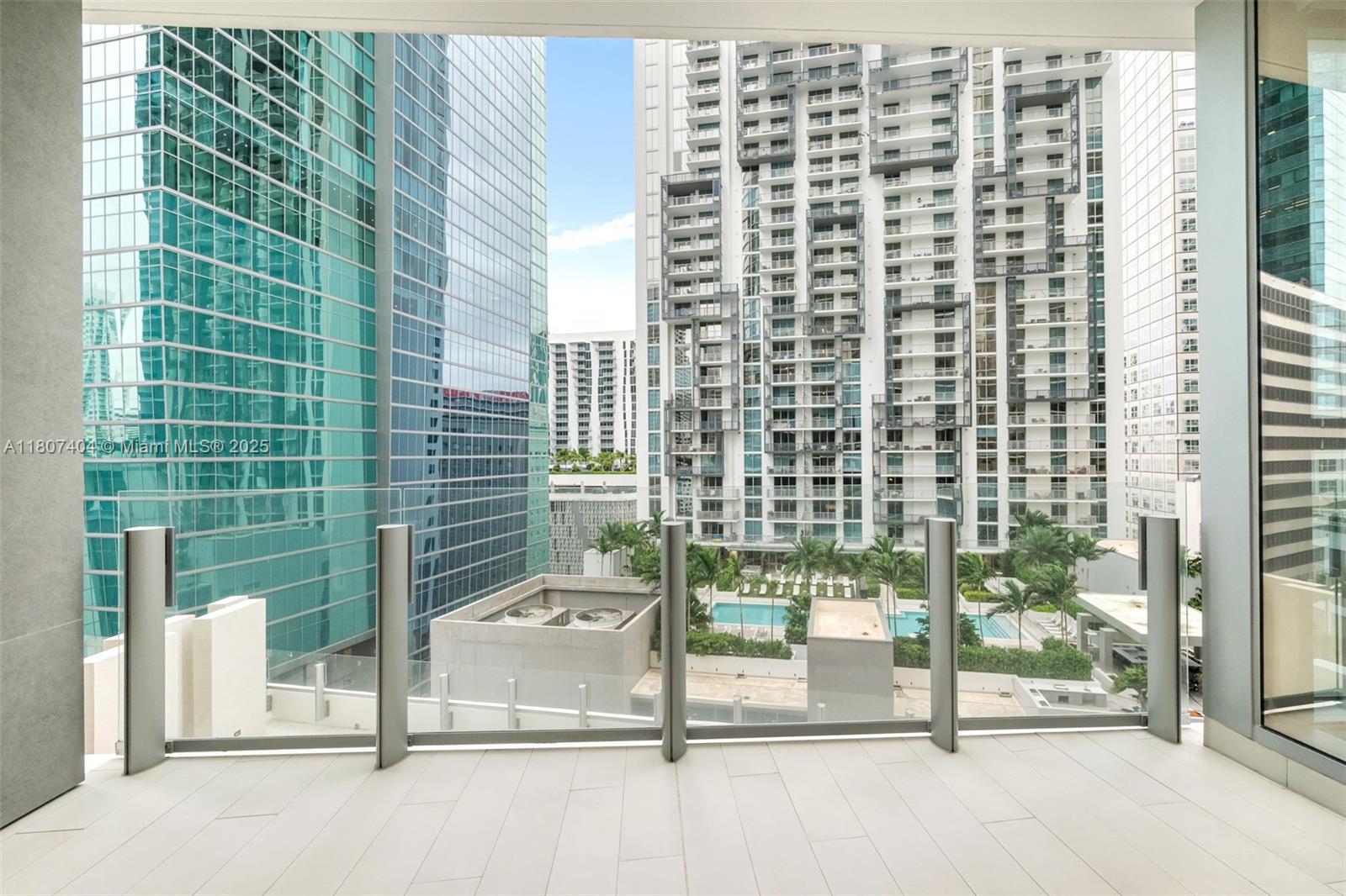 A balcony with a glass railing overlooks a swimming pool and surrounding high-rise buildings — 300 Biscayne Blvd Way # 3509, Miami FL 33131, MIAMI, FL