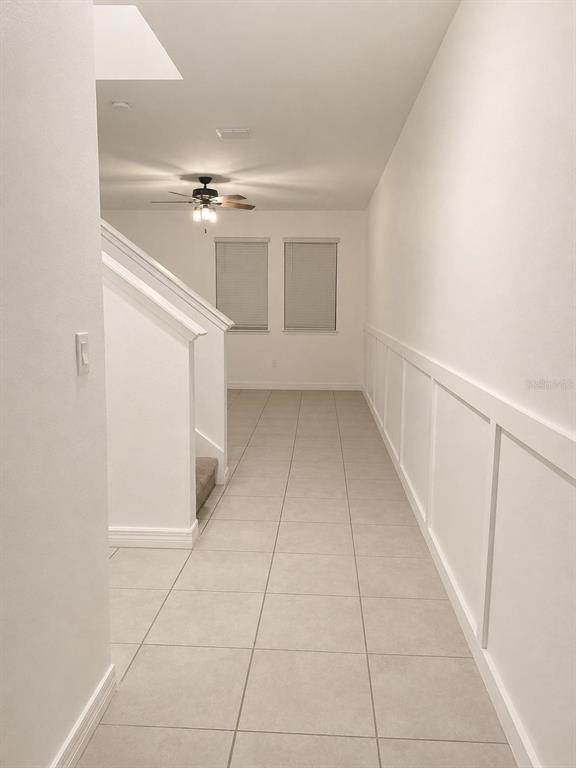 A hallway with tile flooring, wainscoting, and a staircase leads to a room with windows — 15061 WILLOW ARBOR CIRCLE, ORLANDO, FL