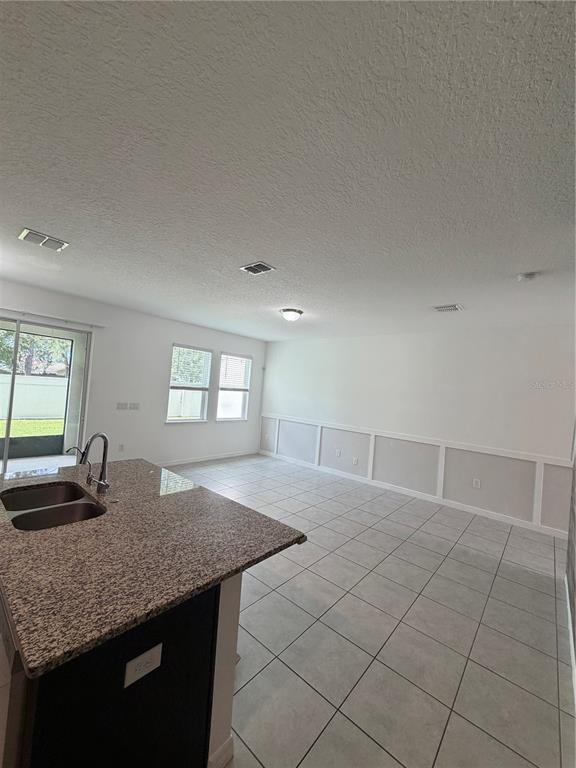 A kitchen island with a granite countertop overlooks a tiled dining area with wainscoting — 15061 WILLOW ARBOR CIRCLE, ORLANDO, FL