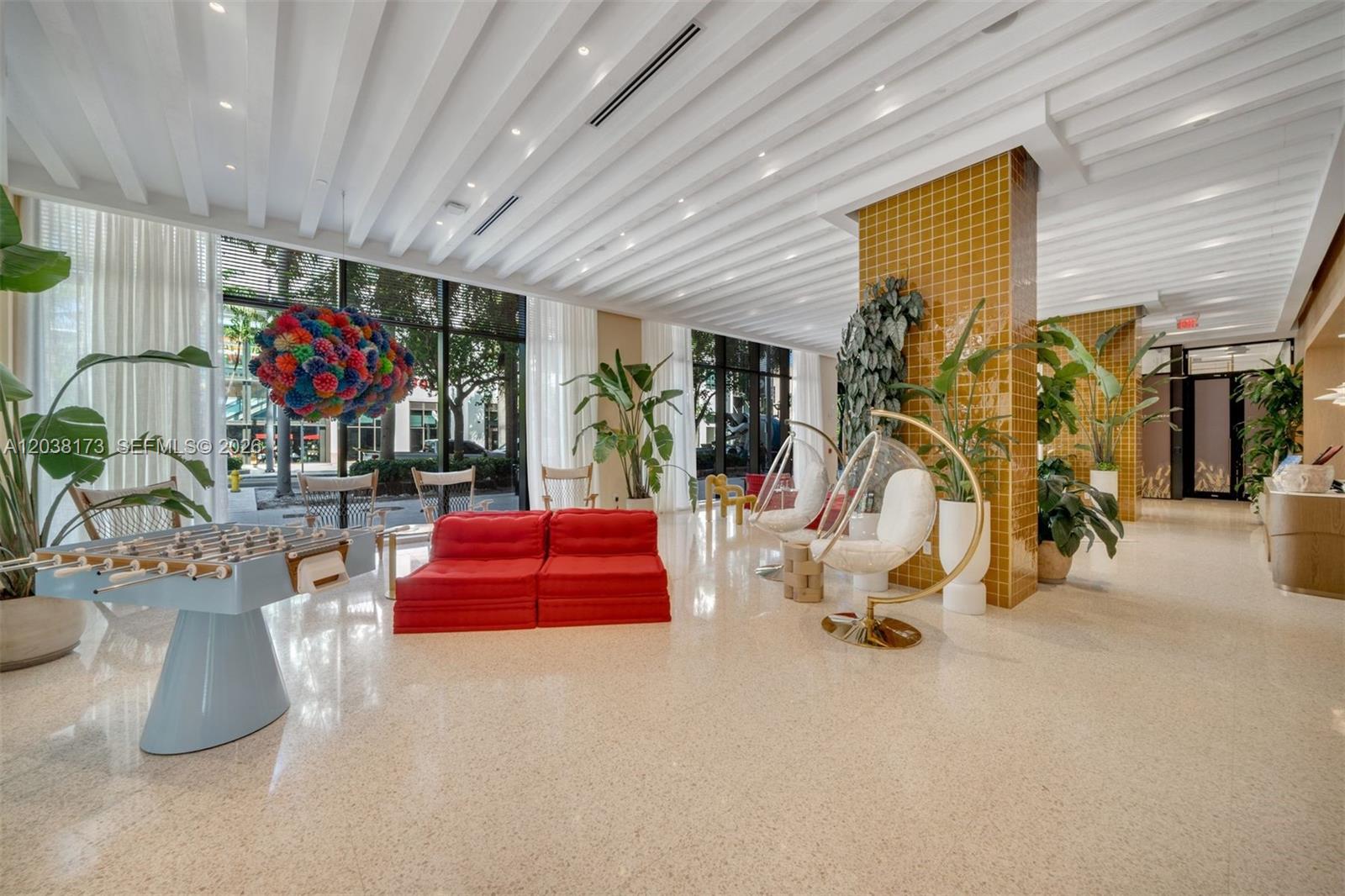 A modern lobby features a foosball table, red sofa, hanging chairs, and yellow tiled columns — 90 32 # 503, Miami FL 33131, MIAMI, FL