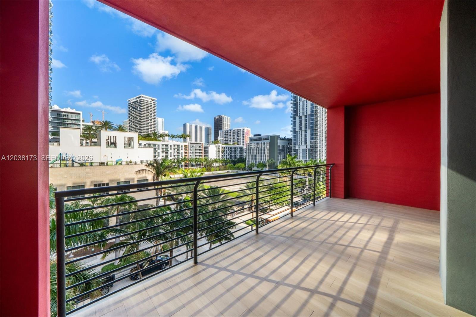 A balcony with red walls, wood-look flooring, and a black railing overlooks a city skyline — 90 32 # 503, Miami FL 33131, MIAMI, FL