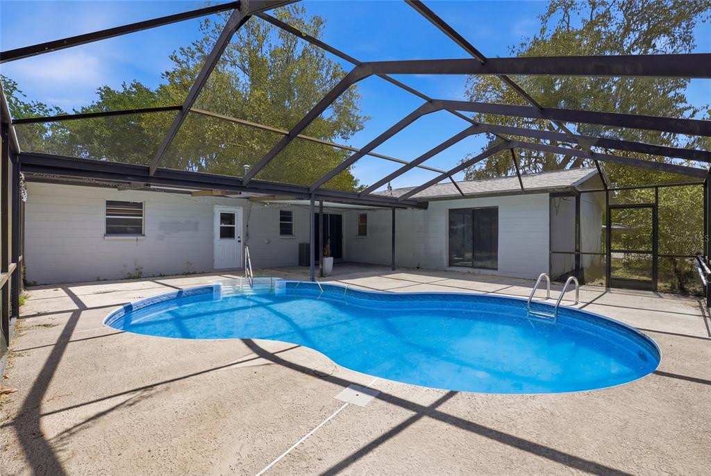 A backyard swimming pool enclosed by a screened lanai attached to a single-story house — 4006 NW 36TH TERRACE, GAINESVILLE, FL