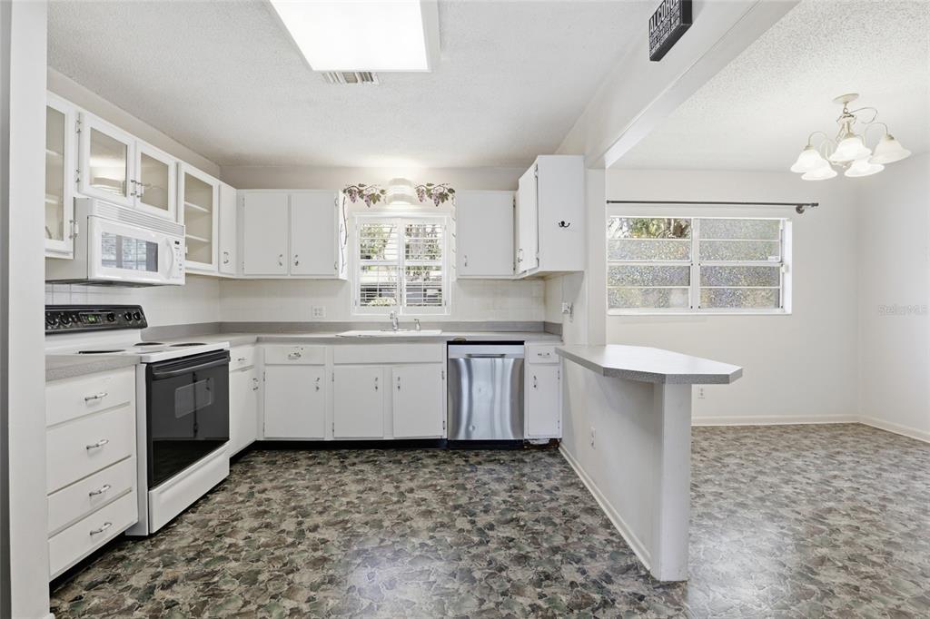 A kitchen with white cabinets, stainless steel appliances, and mottled green and brown flooring — 4006 NW 36TH TERRACE, GAINESVILLE, FL