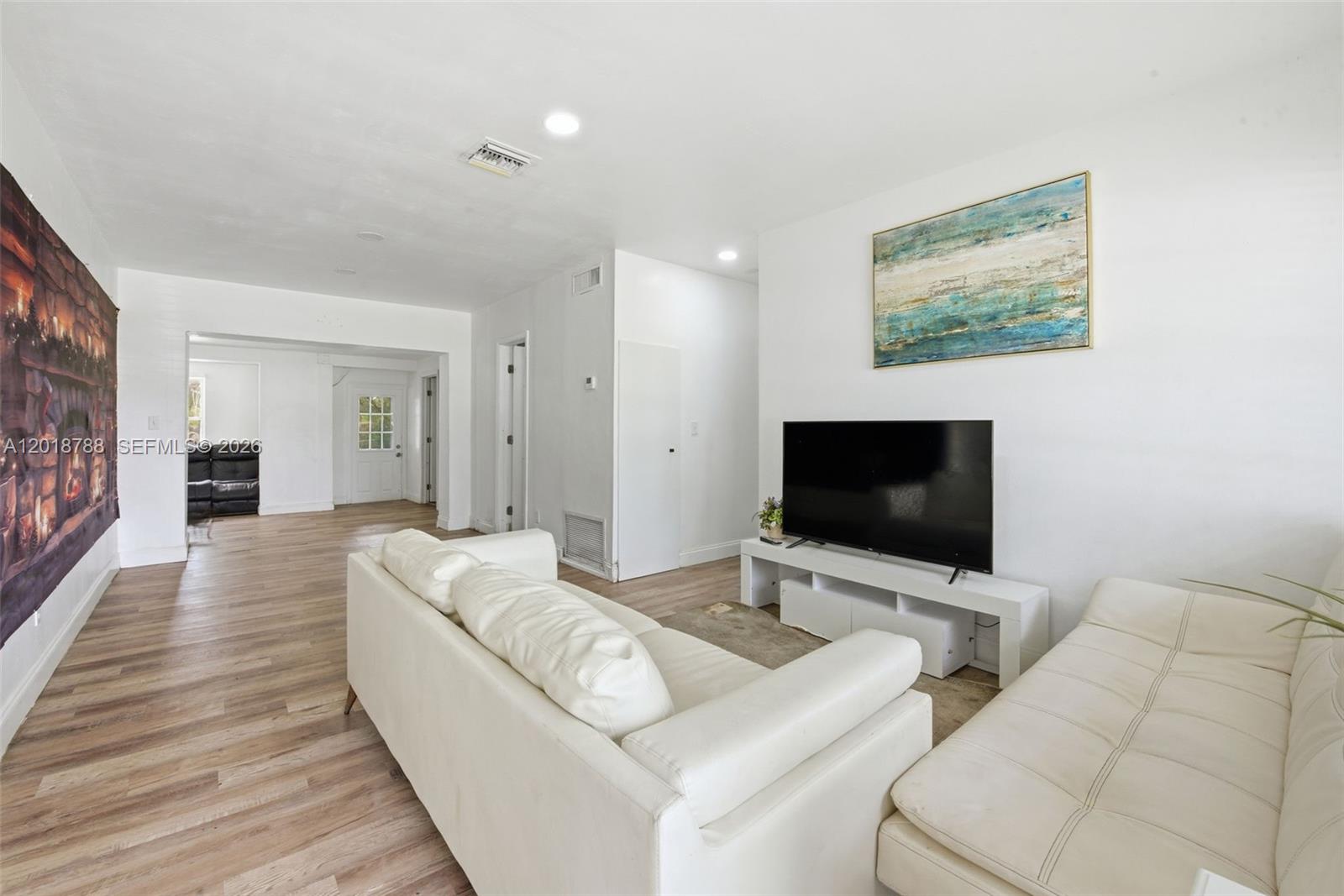 A living room features white leather sofas, a television on a stand, and wood flooring — 4621 SW 31st Dr, West Park FL 33023, WEST PARK, FL