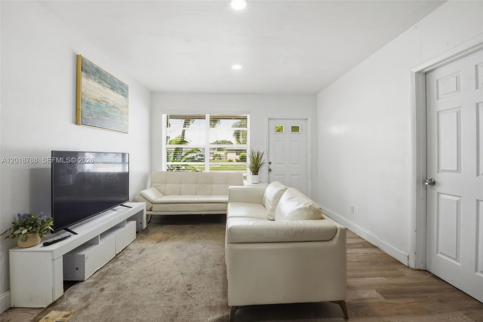 A living room features white walls, a white sofa, a futon, and a television console — 4621 SW 31st Dr, West Park FL 33023, WEST PARK, FL