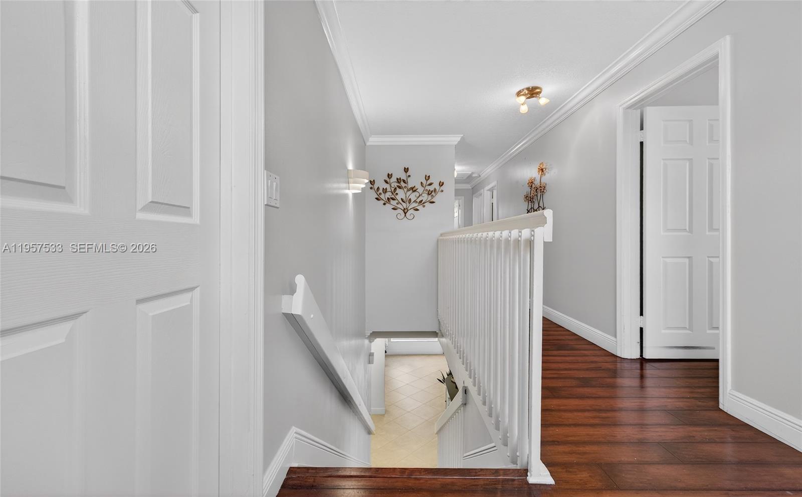 A staircase with white railings leads down from a hallway with dark wood flooring — 1485 NW 129th Ter, Sunrise FL 33323, SUNRISE, FL