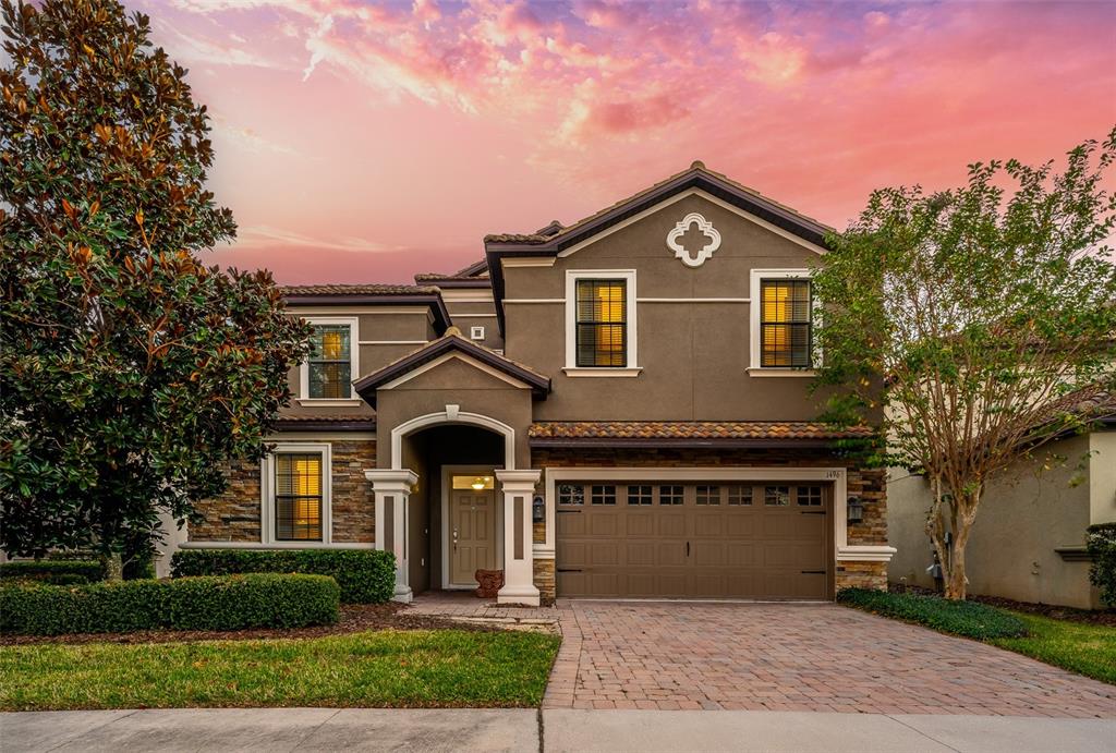 A two-story house with a stone and stucco exterior, a paved driveway, and a garage — 1496 MOON VALLEY DRIVE, DAVENPORT, FL